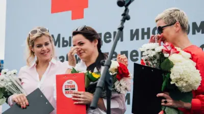 Слева направо: Вероника Цепкало в белой блузке, Светлана Тихановская с папкой 